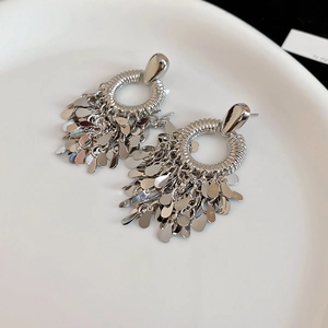 Close-up of silver geometric earrings with layered teardrop sequins and fringe detail