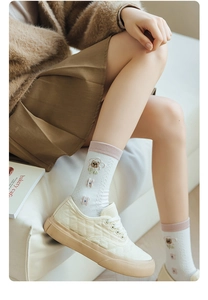 Close-up of white cotton socks with bear embroidery paired with beige sneakers on model
