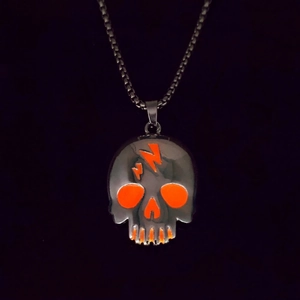 Close-up of a skull pendant with orange lightning and eyes on a black box chain
