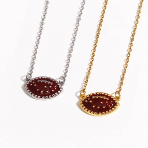 Detail of silver and gold football necklaces with red enamel pendants on white background
