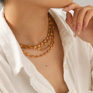 Close-up of triple-layered 18k gold plated necklace on model with refined textured chains