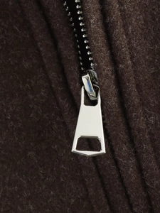 Detail shot of a silver metal zipper on a premium dark brown wool fabric jacket