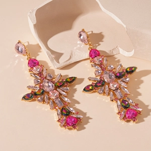 Macro shot of vintage cross earrings with pink crystals and teardrop gems on a stone base