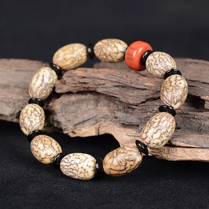 Natur Goldfaden Bodhi Armband mit roter Perle auf dunklem altem Holz Hintergrunddeko