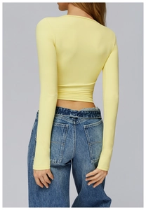 Rear view of a pale yellow slim fit cropped athletic top with smooth brushed texture