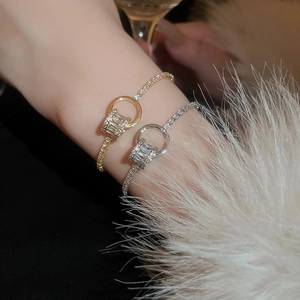 Détail de bracelets réglables dorés et argentés avec pendentifs anneaux en zircon au poignet