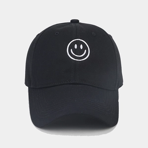 Close-up of white smiling face embroidery on a black cotton baseball cap detail