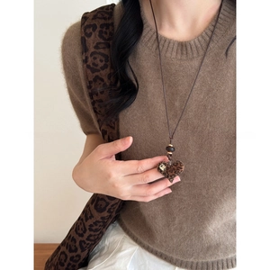 Detail of flocked leopard heart pendant with dark brown cord on a brown sweater