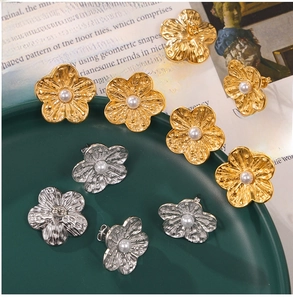 Detailed view of textured metal flower earrings with white pearl centers in gold and silver