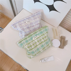 Detail view of plaid tweed makeup bags in pastel purple and mint green with zip closure