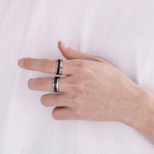Detail of 8mm silver Roman numeral ring and black carbon fiber ring set worn on finger