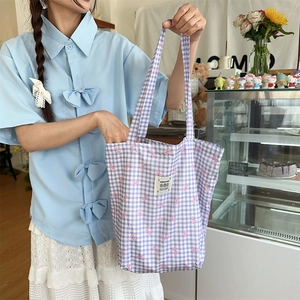 Detail of purple plaid canvas tote bag with pink bows and stitched LOVE label