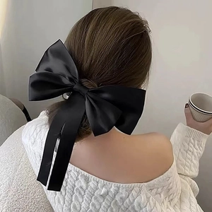 Close-up of elegant black satin bow hair clip with long ribbons worn on the back of head
