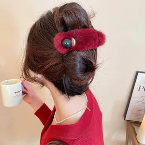 Chic burgundy plush hair claw with Lucky charm, styled on a woman's hair bun