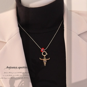 Bohemian gold bull head necklace with red evil eye bead on model wearing a beige blazer