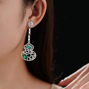 Macro shot of a long gourd-shaped earring with green gemstones and pavé diamonds