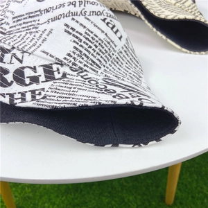 Détail du chapeau bob en toile imprimé journal avec coutures précises et doublure noire