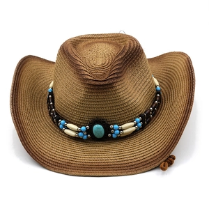 Dettaglio cappello cowboy in paglia con perline turchesi e fascia etnica decorativa
