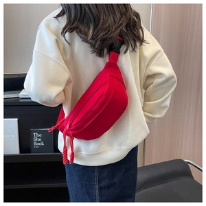 Detail of red canvas crossbody bag with adjustable strap and braided zipper pullers