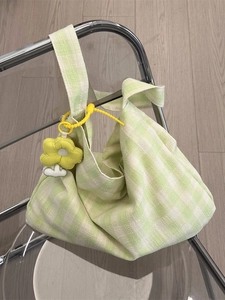 Chic green checkered canvas tote bag with yellow flower pendant on a folding chair