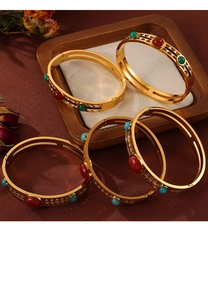 Detail of vintage gold-plated bangles with colorful enamel inserts on a wooden tray