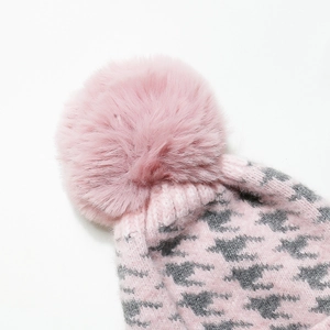 Dettaglio berretto in maglia pied de poule rosa con un grande pompon in pelliccia sintetica