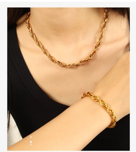 Close-up of gold-plated twisted rope chain necklace and bracelet set on model