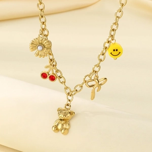 Detailansicht der Goldkette mit Kirsch-, Gänseblümchen- und Smiley-Anhängern auf Seide