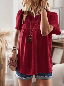 Detailed macro view of the intricate hollow lace and tassel on this red round neck top