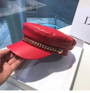 Detail view of red leather nautical hat with gold chain and metal buckle accents