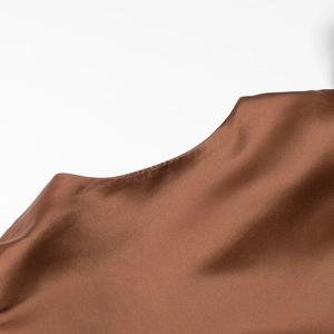 Detail of elegant brown satin blouse showing glossy fabric texture and puff sleeve seam
