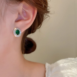 Close-up of vintage oval earring featuring green zirconia stone with double halo diamonds