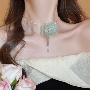 Detail of floral necklace featuring green tulle flower, pearls and invisible chain