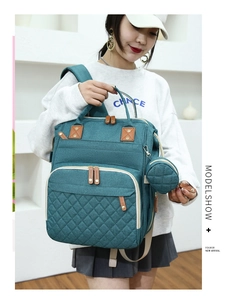 Detail of teal quilted diaper bag with leather zipper pulls and round pacifier pouch
