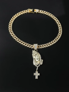Macro view of iced out golden Cuban chain with praying hands and cross pendant details