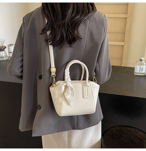 Detail of white lychee grain leather bucket bag with silk scarf on a grey blazer