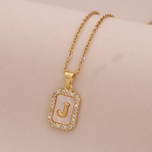 Gros plan du pendentif rectangulaire doré avec la lettre J et incrustation de nacre
