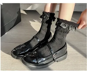 Detail of black patent leather Mary Jane shoes paired with lace ruffle Lolita socks