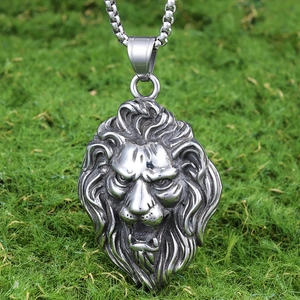Detail of silver stainless steel lion head pendant hanging against green moss background