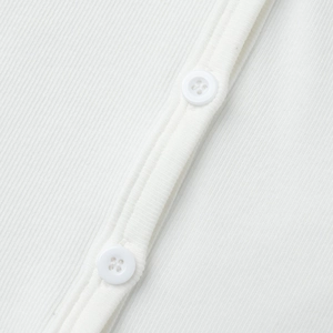 Macro detail of white ribbed knit fabric and four-hole buttons on a cropped cardigan