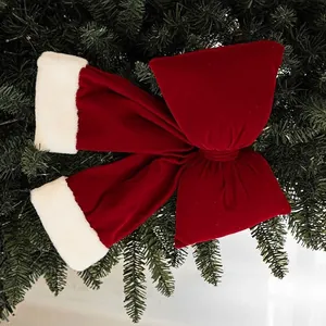 Large red velvet Christmas bow with white faux fur trim hanging on a festive tree