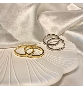 Gold and silver S925 sterling silver hoop earrings displayed on a white shell tray