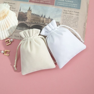 Detail view of cream and white plush drawstring pouches with elegant jewelry staging