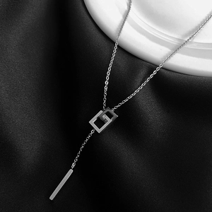 Minimalist silver interlocking square pendant necklace on elegant satin background