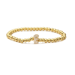 Detailed shot of golden bead bracelet featuring a micro-paved cubic zirconia letter E charm