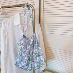 Detail of floral tote bag hanging on a rack showing purple flower patterns and thin cotton fabric