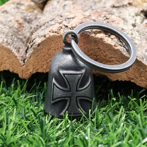 Detail of vintage Iron Cross motorcycle bell with textured silver finish on wood and grass