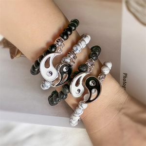 Close-up of yin yang charm on beaded couples bracelets with matte black and white marble stone