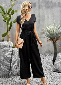 Close-up of black V-neck short sleeve jumpsuit with waist tie in a desert setting