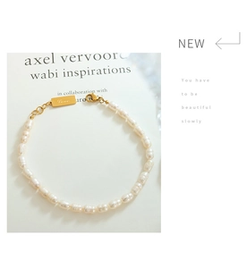 Detail of 18K gold letter pendant and freshwater pearls over an artistic book